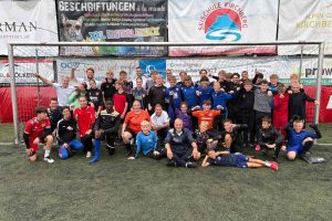 Groepsfoto van deelnemers en begeleiders van het Keeperskamp 2025 op het voetbalcomplex van SC Kirchberg in Tirol. Het plezier dat ze gehad hebben straalt van hun gezichten af.
